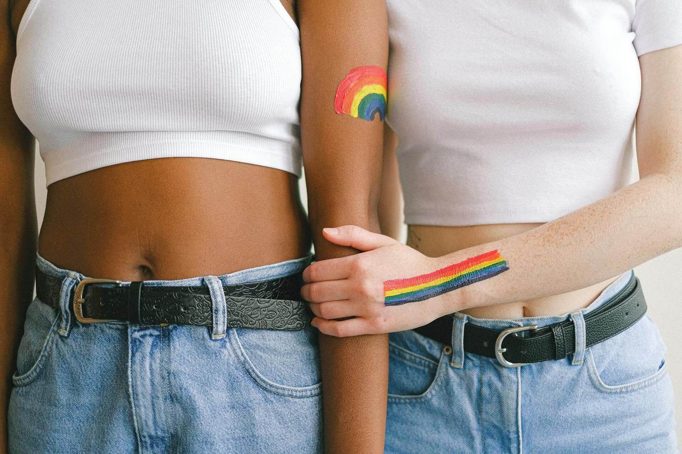 Lesbian couple with rainbow pride arm paint, wearing matching white tops and jeans